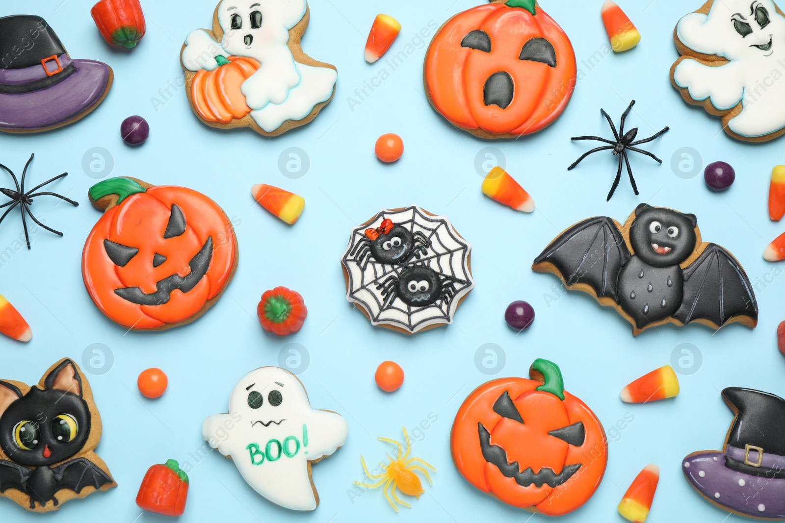 Photo of Tasty cookies and sweets for Halloween party on light blue background, flat lay