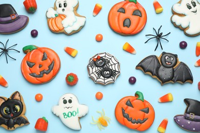 Tasty cookies and sweets for Halloween party on light blue background, flat lay