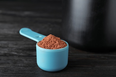 Photo of Scoop of chocolate protein powder on black table