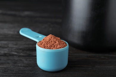 Scoop of chocolate protein powder on black table