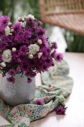 Photo of Beautiful flowers and bright cloth on wooden table