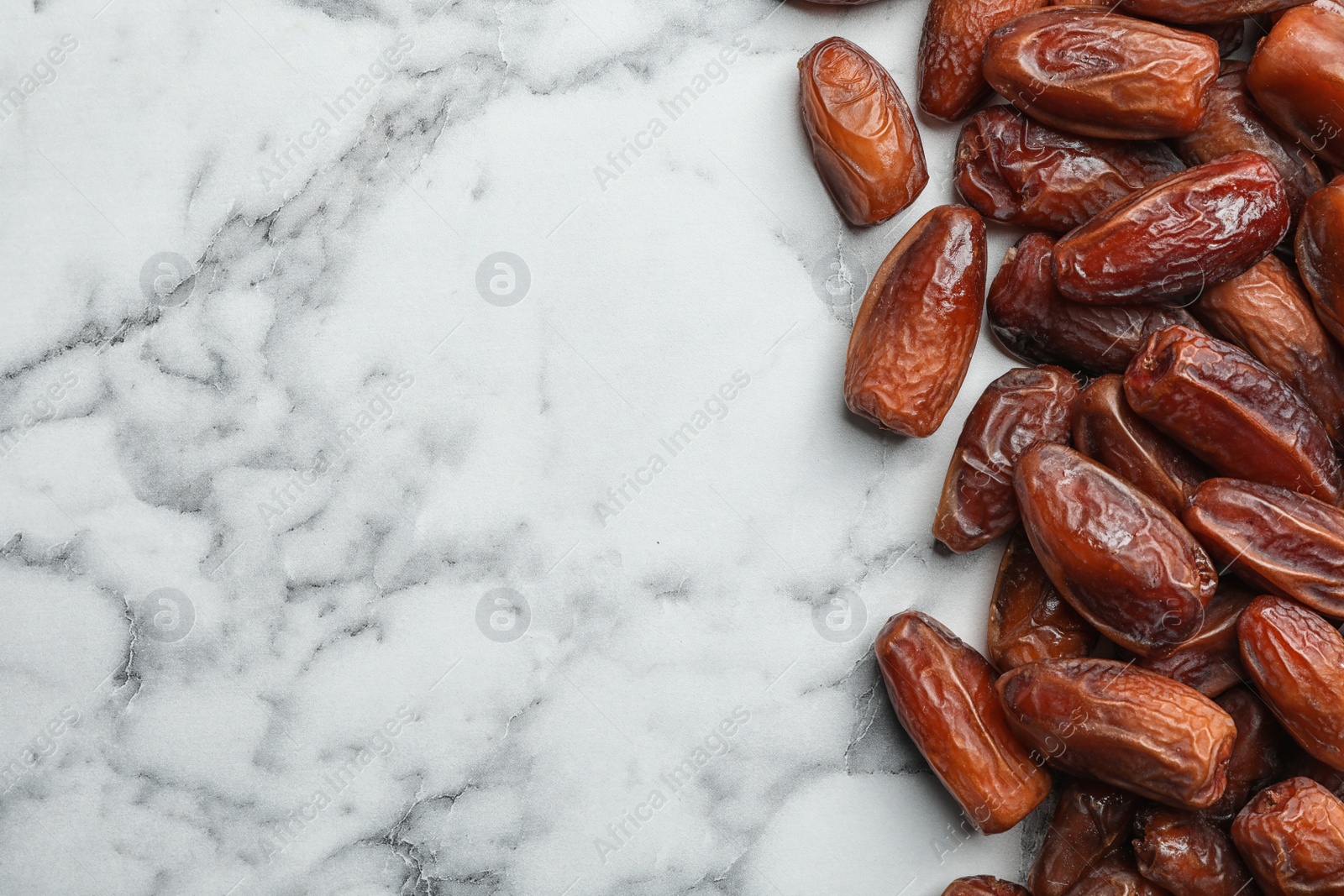 Photo of Sweet dried date fruits on marble background, top view. Space for text