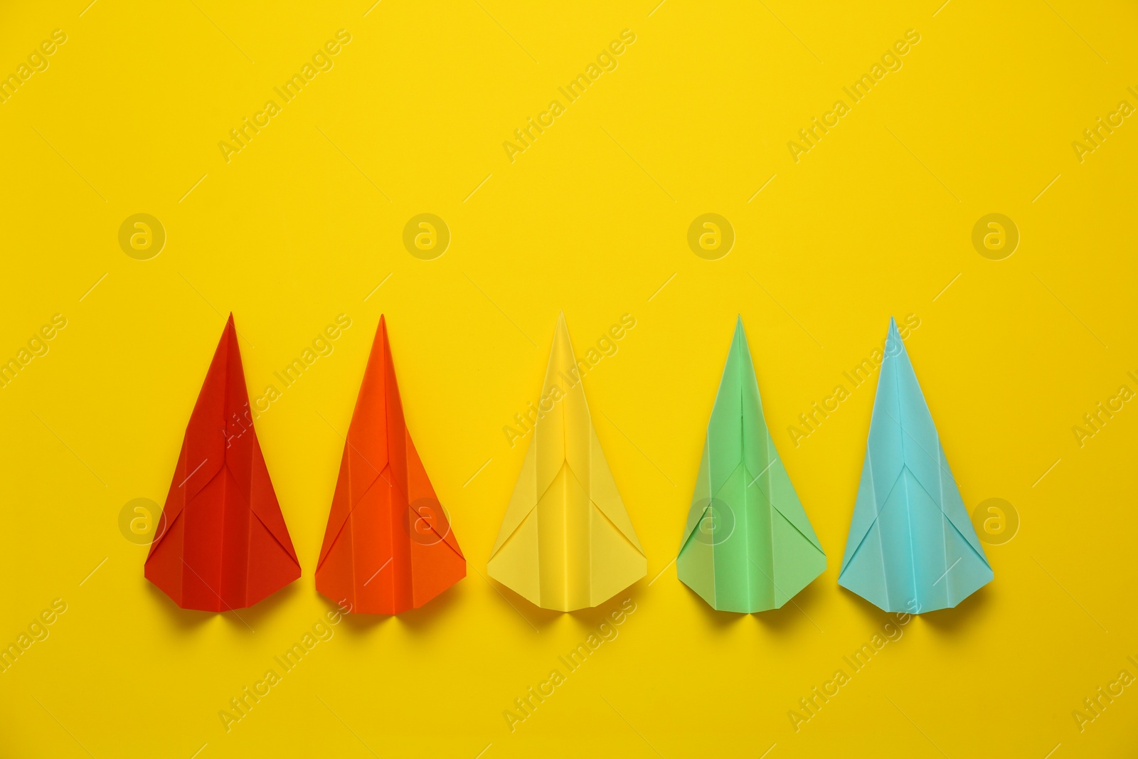 Photo of Different handmade paper planes on yellow background, flat lay. Space for text