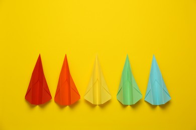 Photo of Different handmade paper planes on yellow background, flat lay. Space for text