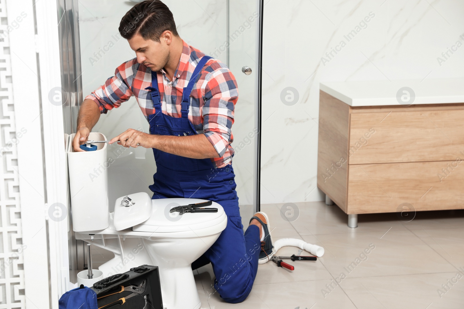 Photo of Professional plumber working with toilet bowl in bathroom