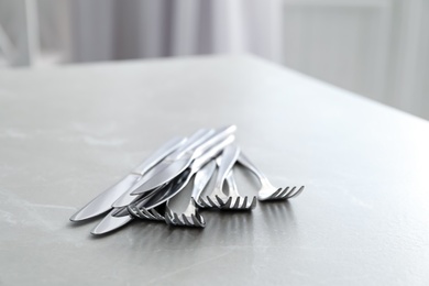 Photo of Knives and forks on light grey marble table, closeup
