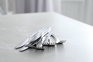 Knives and forks on light grey marble table, closeup