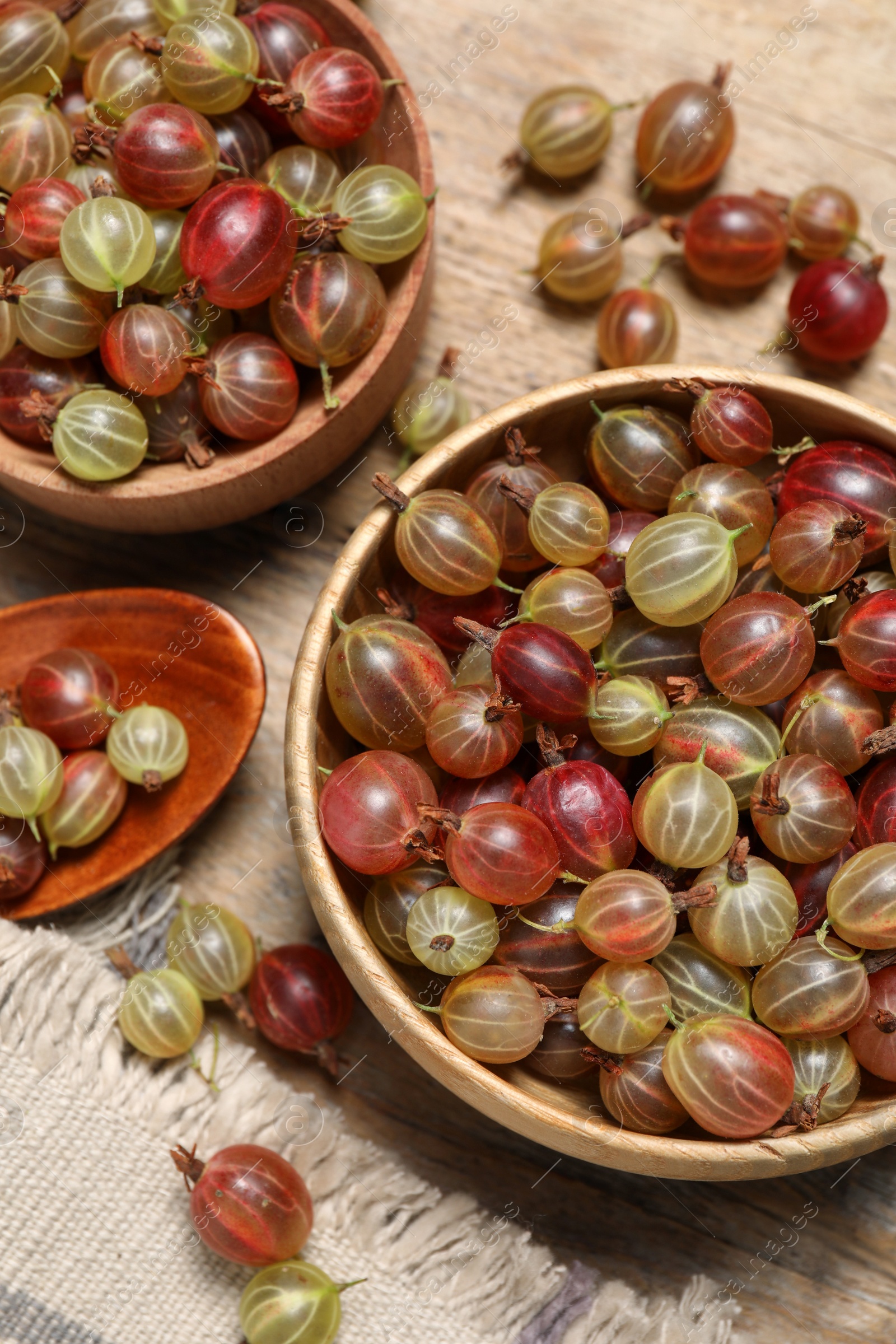 Photo of Many fresh ripe gooseberries on wooden table, flat lay