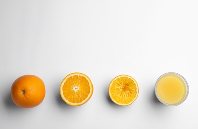 Fresh and squeezed oranges with juice in glass on white background, top view