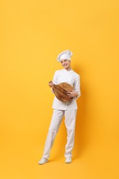 Photo of Professional chef with serving board having fun on yellow background