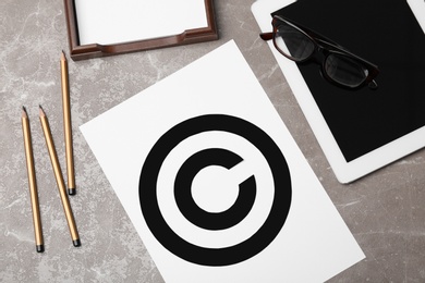 Photo of Sheet of paper with copyright symbol and tablet on grey background. Law compliance concept