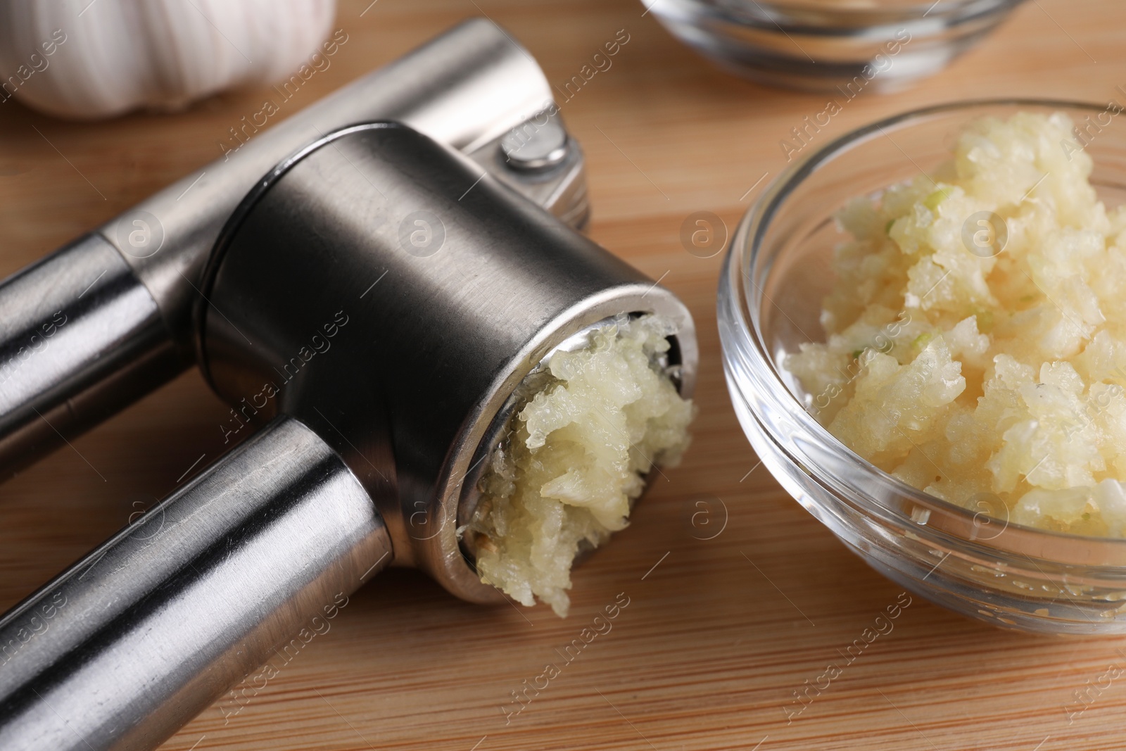 Photo of Garlic press and mince on wooden table, closeup