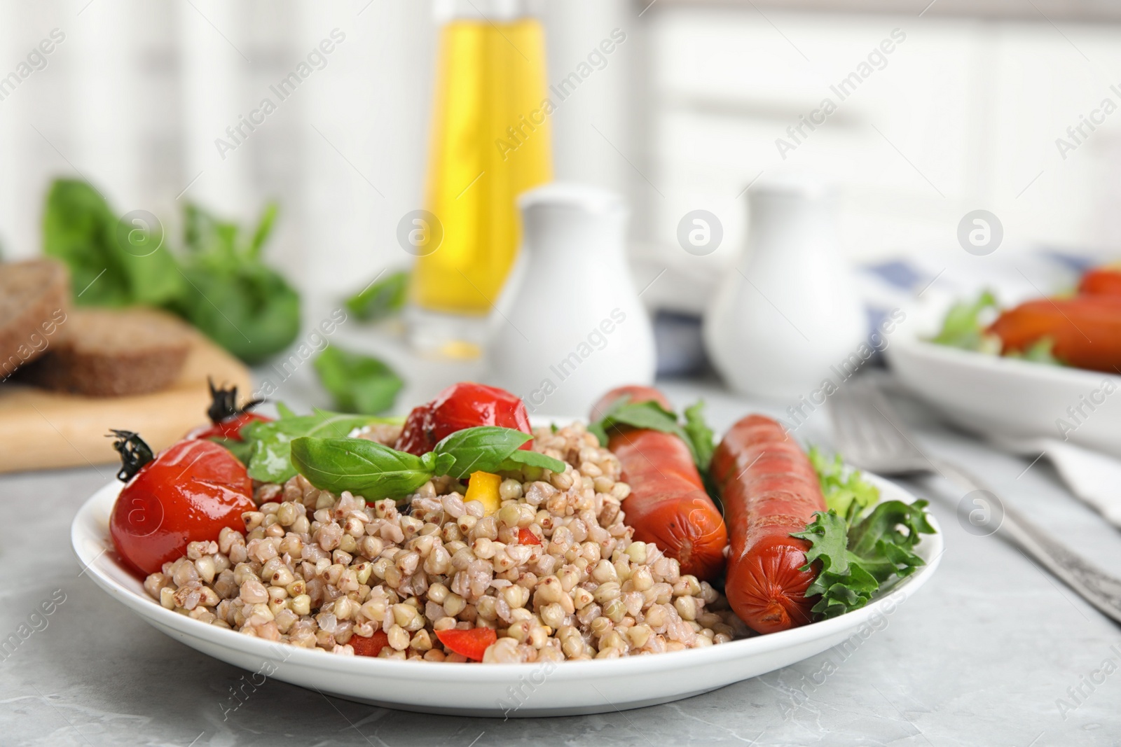 Photo of Tasty buckwheat porridge with sausages on light grey marble table indoors. Space for text