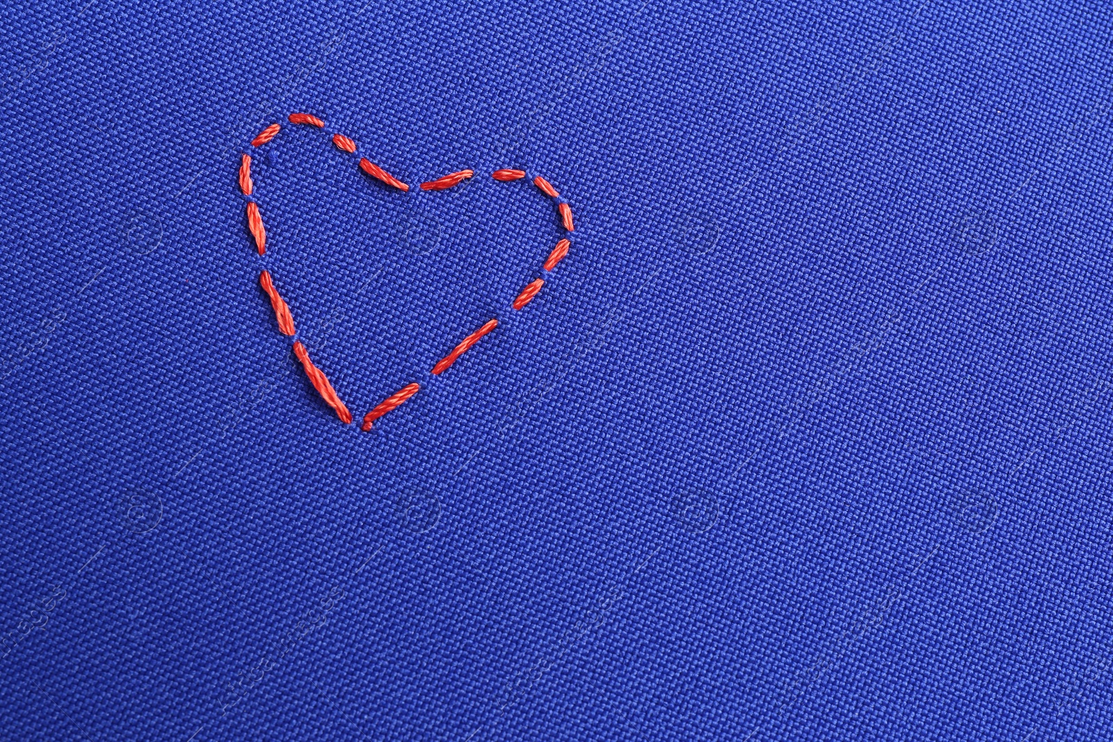 Photo of Embroidered heart on blue cloth, top view