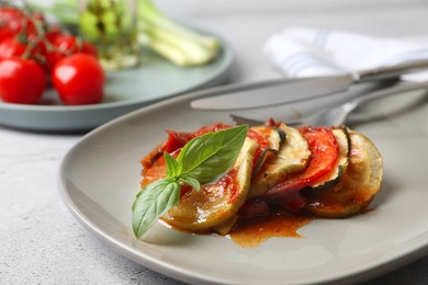 Photo of Delicious ratatouille served with basil on light grey table, closeup