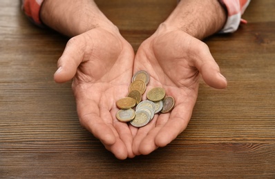 Photo of Senior man holding coins in hands at table, closeup