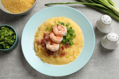 Photo of Plate with fresh tasty shrimps, bacon, grits and green onion on grey table, flat lay