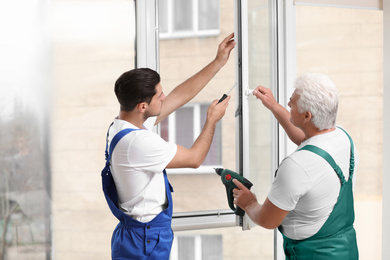 Construction workers repairing plastic window with screwdriver indoors