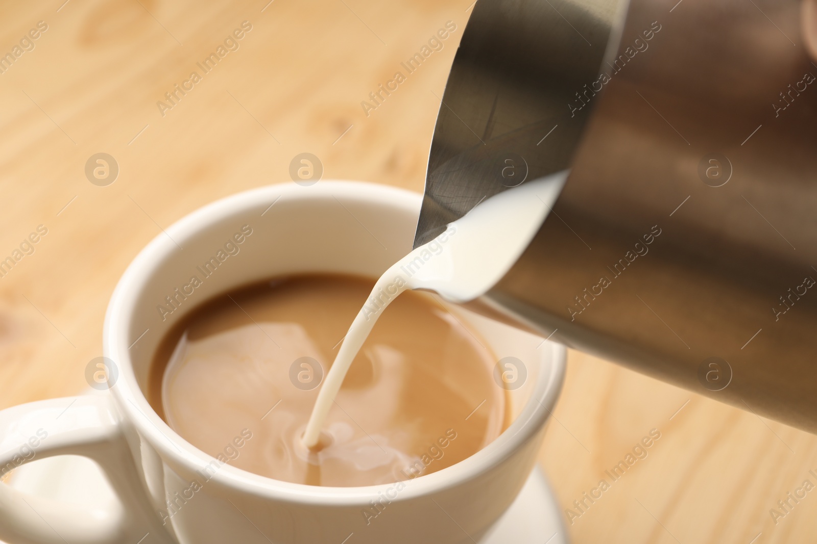 Photo of Pouring milk into cup at table, closeup