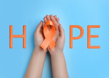 Image of Word HOPE and woman with orange awareness ribbon on light blue background, top view  