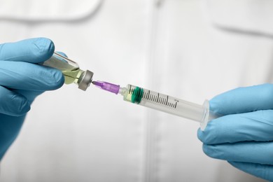 Photo of Doctor filling syringe with hepatitis vaccine from glass vial, closeup