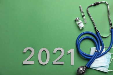 Photo of Flat lay composition with coronavirus vaccine on and number 2021 green background, space for text