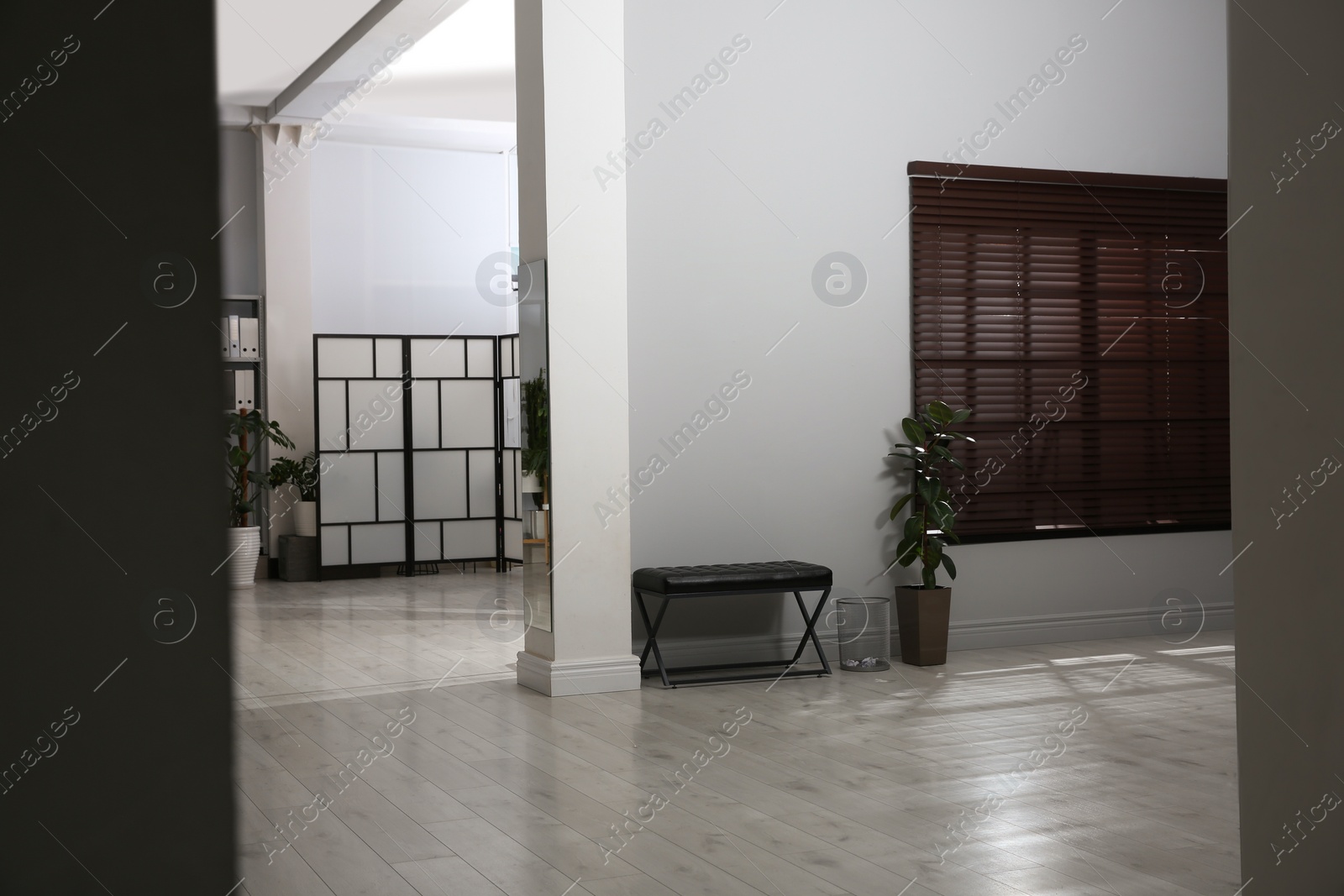 Photo of Empty long office corridor with bench and green potted plants