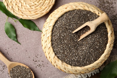 Photo of Wicker box and wooden spoon with chia seeds on table, flat lay