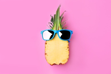 Photo of Funny pineapple with sunglasses on color background