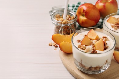 Photo of Delicious yogurt with fresh peach and granola on white wooden table, space for text
