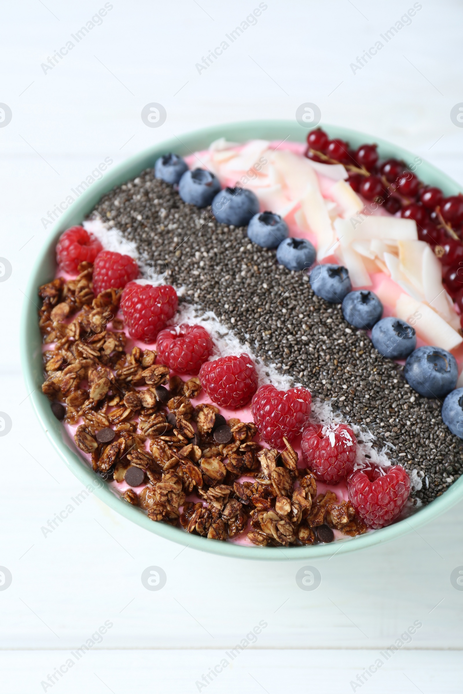 Photo of Tasty smoothie bowl with fresh berries and granola on white table