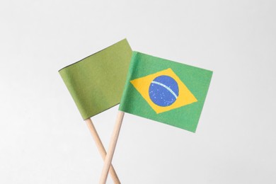 Photo of Small paper flag of Brazil and olive one on light background, closeup