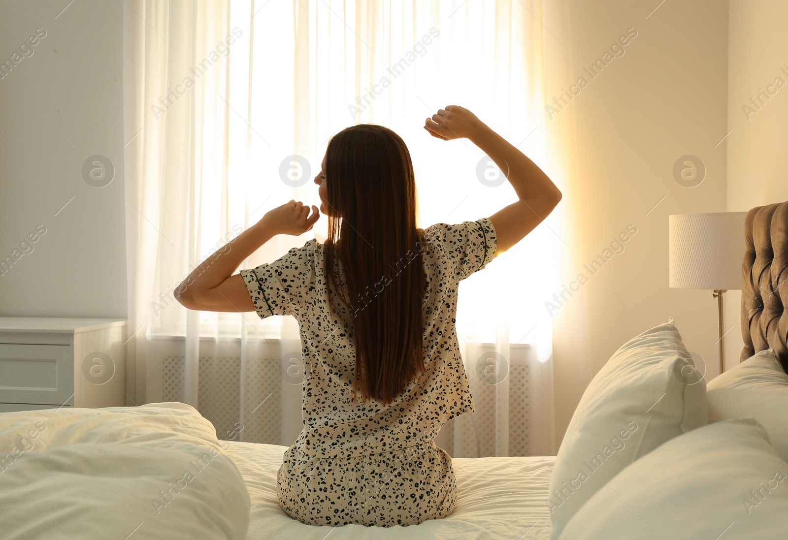 Photo of Young woman stretching on bed at home. Lazy morning