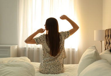 Photo of Young woman stretching on bed at home. Lazy morning