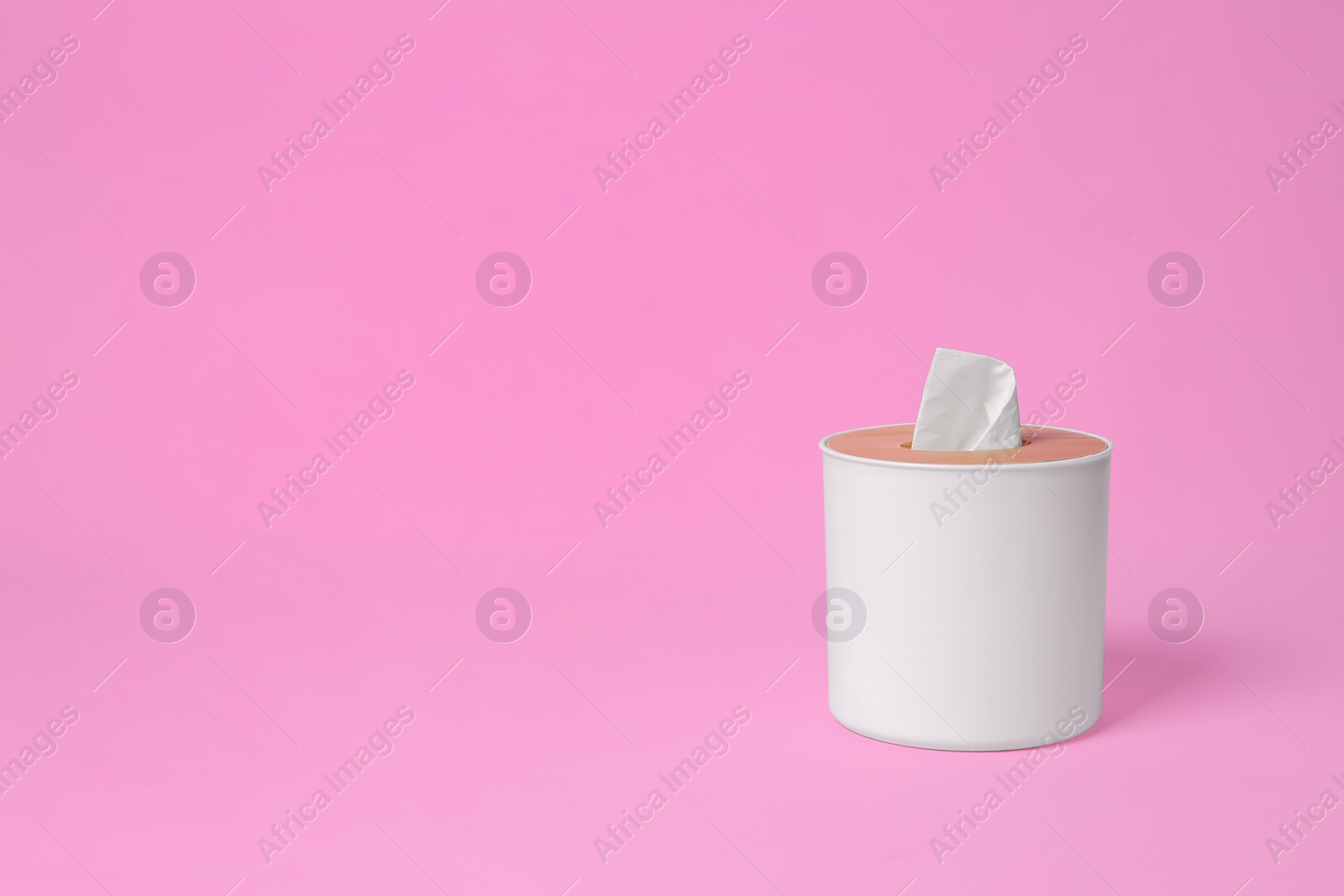 Photo of Holder with paper tissues on pink background. Space for text