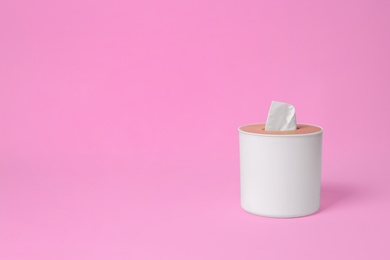 Photo of Holder with paper tissues on pink background. Space for text