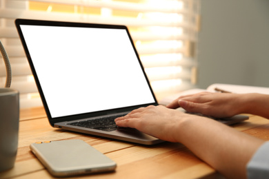 Woman working with modern laptop at wooden table, closeup. Space for design