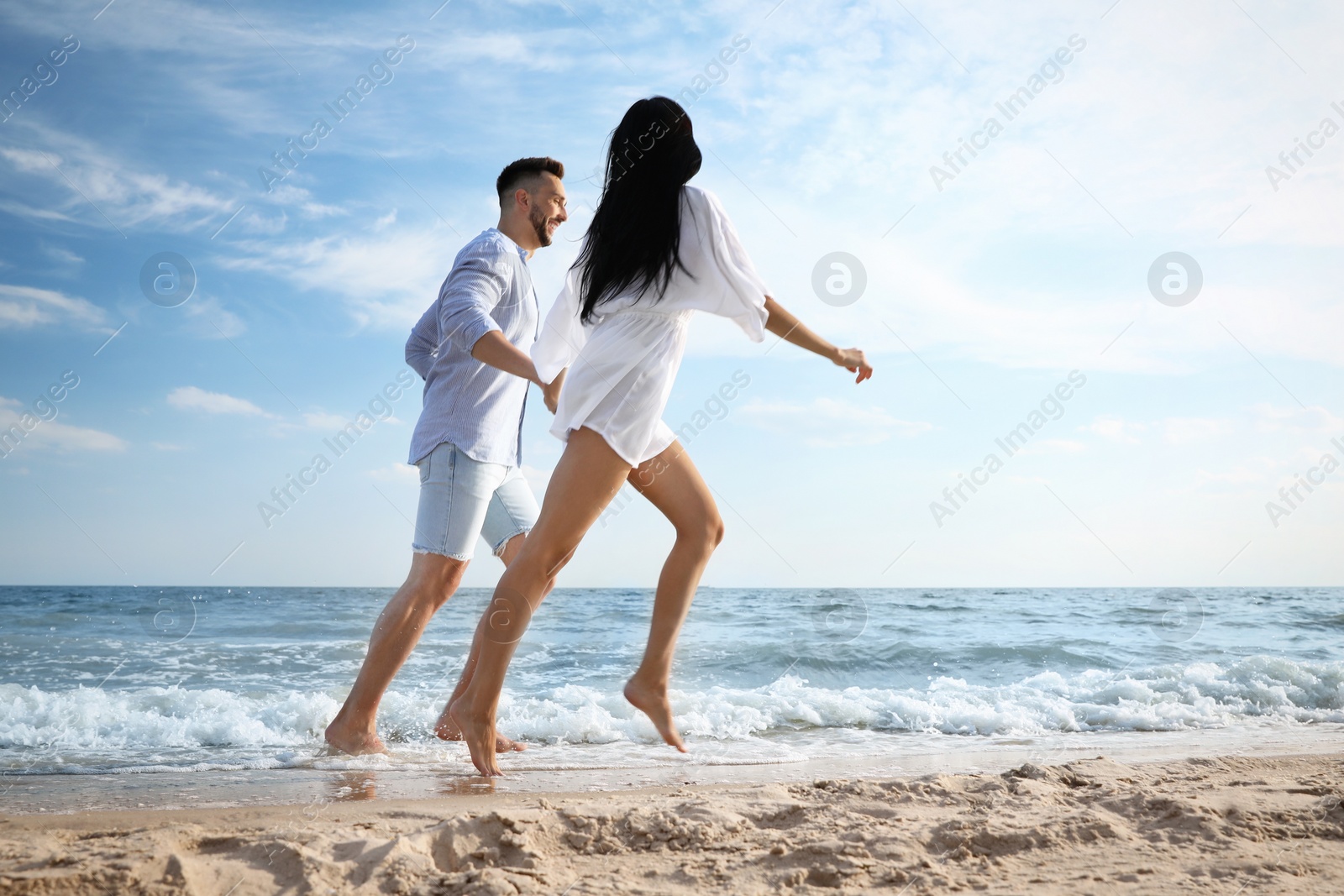 Photo of Happy young couple running together on beach