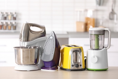 Photo of Household and kitchen appliances on table against blurred background