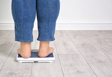 Photo of Overweight woman using scales indoors