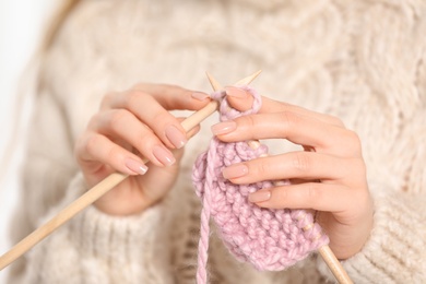 Photo of Young woman in cozy warm sweater knitting with needles, closeup