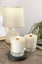 Photo of Burning soy candles with wooden wicks and decor on grey table