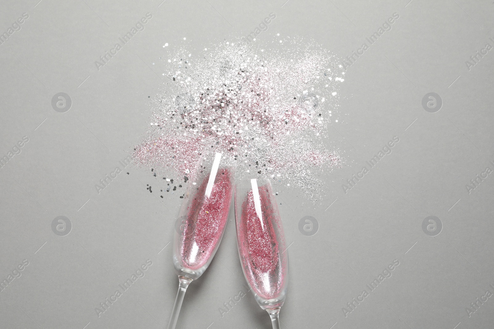 Photo of Flat lay composition with champagne glasses for celebration on grey background