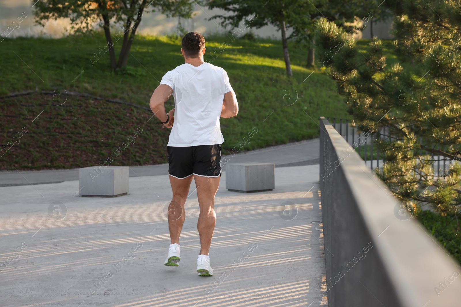 Photo of Man running outdoors on sunny day, back view