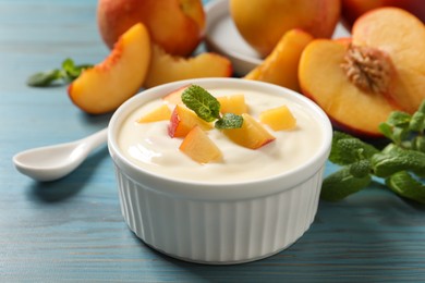 Photo of Delicious yogurt with fresh peach and mint on light blue wooden table