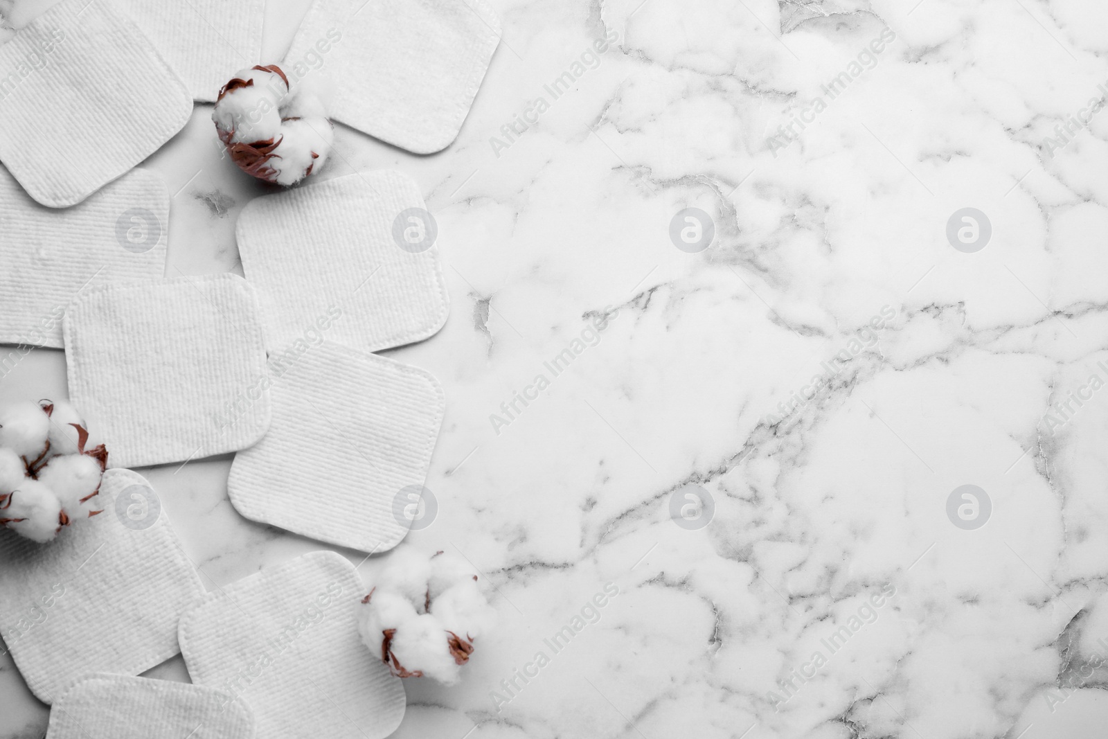 Photo of Flat lay composition with many clean cotton pads and flowers on white marble table. Space for text