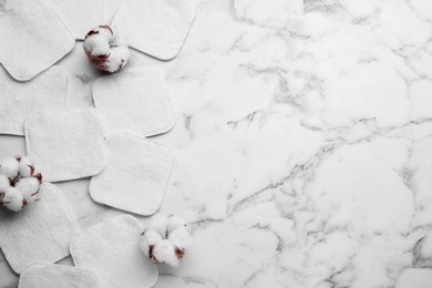 Photo of Flat lay composition with many clean cotton pads and flowers on white marble table. Space for text