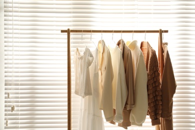 Photo of Rack with stylish women's clothes indoors. Modern interior design
