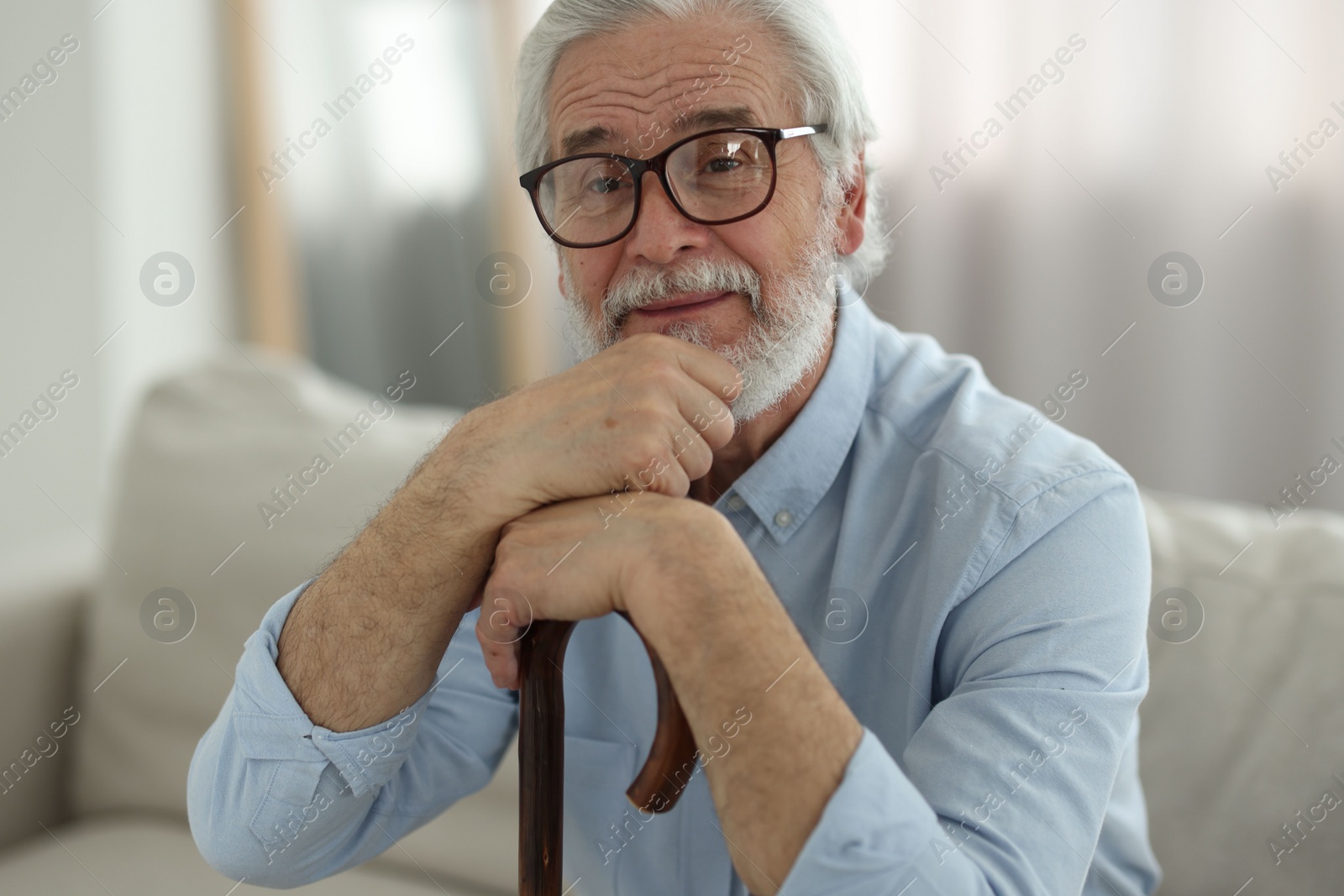 Photo of Portrait of grandpa with glasses and walking cane on sofa indoors