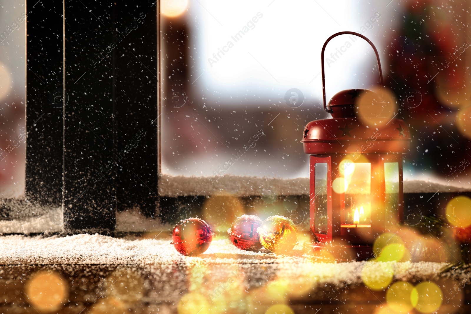 Image of Red lantern with candle and bells near window outdoors. Christmas eve
